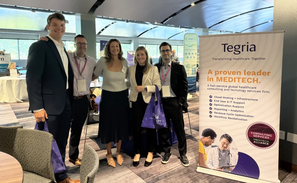 Tegria team with MEDITECH sales reps next to banner at MEDITECH LIVE 2025
